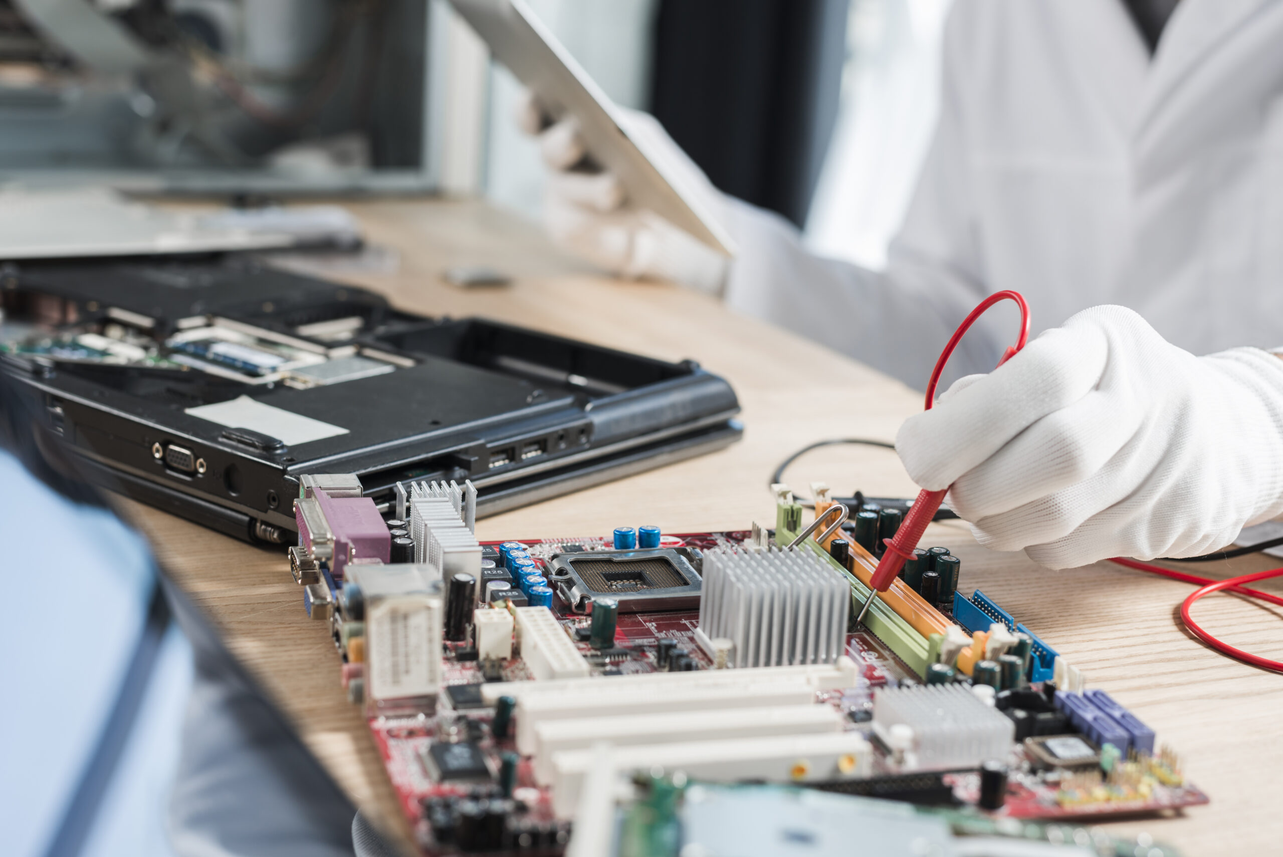 Home male technician examining mother board with digital multimeter