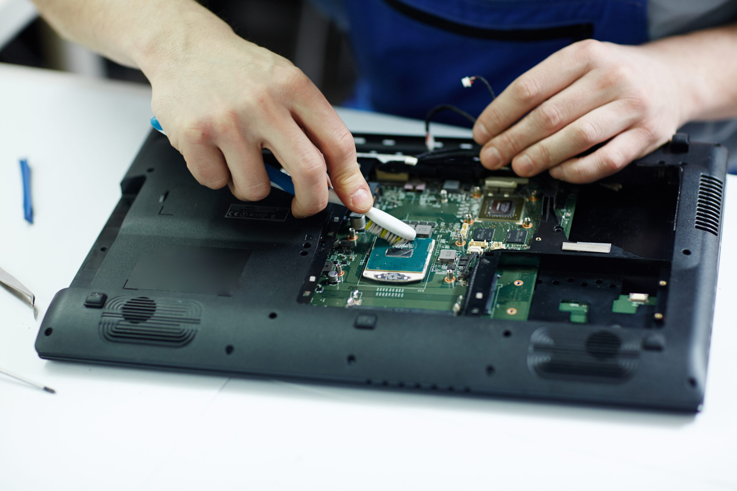 Home technician clearing circuit board of disassembled laptop